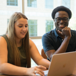 Man and woman look at laptop